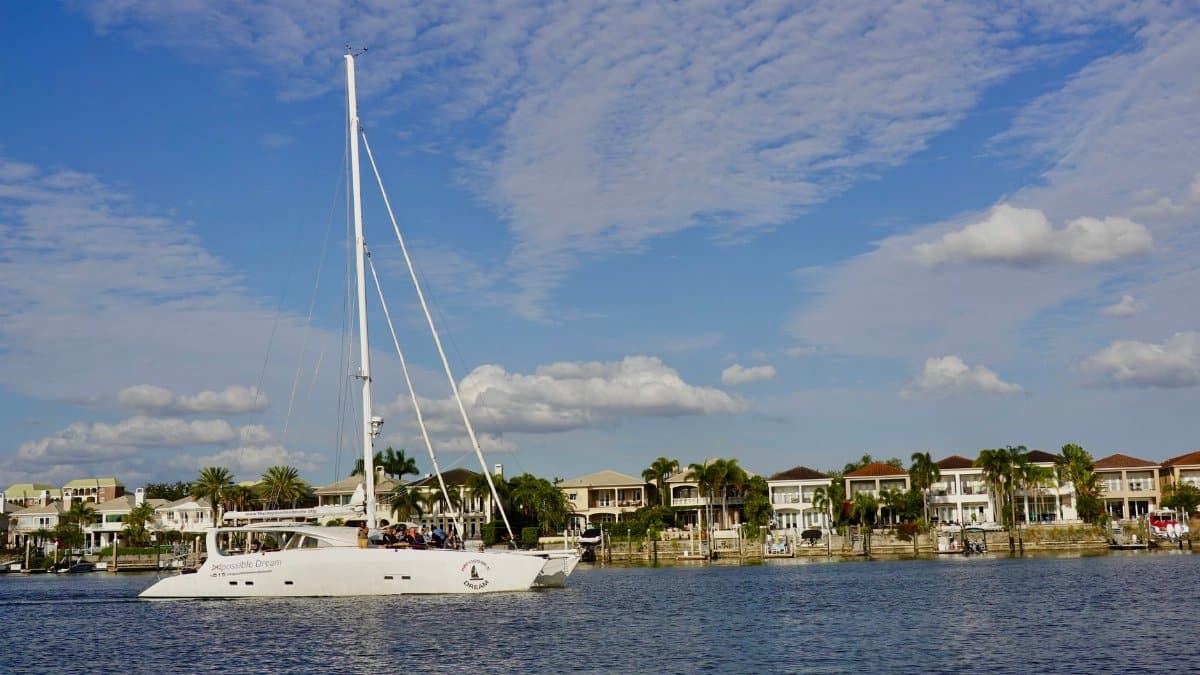 Yacht cruising in scenic Tampa Bay with waterfront homes and clear skies.