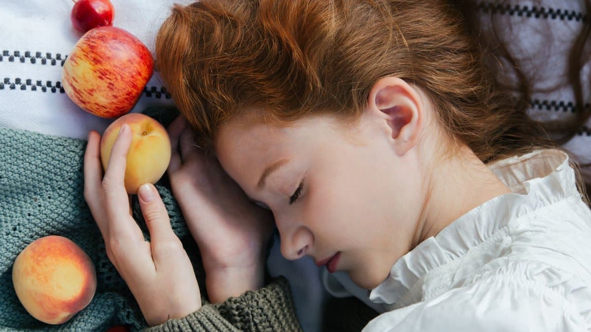 Serene image of a woman with closed eyes holding fruit. Captures tranquility and nature.