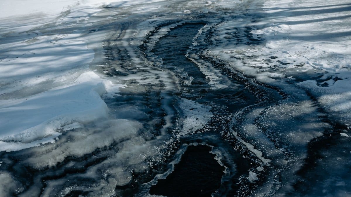 Abstract aerial view of a frozen river with striking ice melting patterns captured during winter.