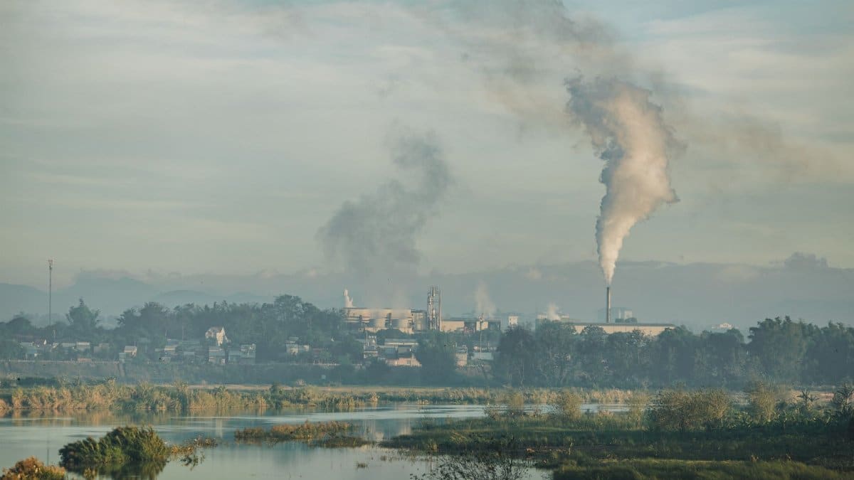A factory emitting smoke over a natural landscape in Kon Tum, Vietnam.