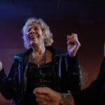 Senior woman wearing a black leather jacket enjoying a fun night out dancing at a club.