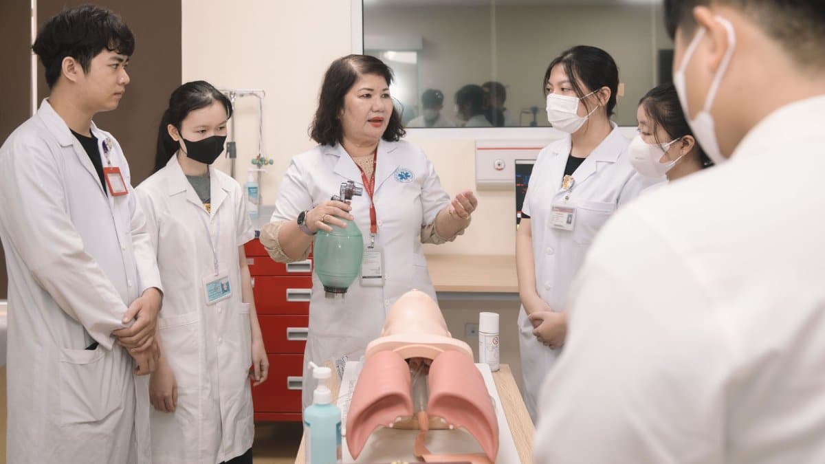 Group of medical students practicing skills with a training mannequin in a classroom setting.