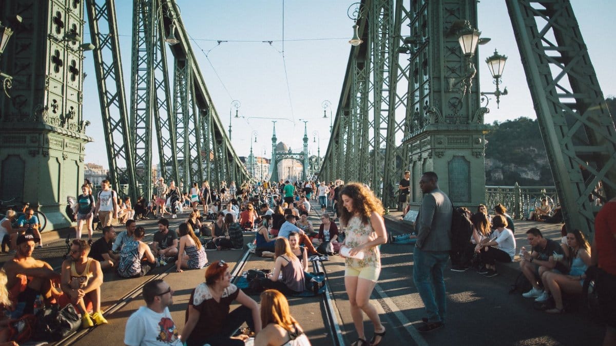 People enjoying a summer festival on Liberty Bridge, Budapest, filled with a youthful crowd and vibrant atmosphere.