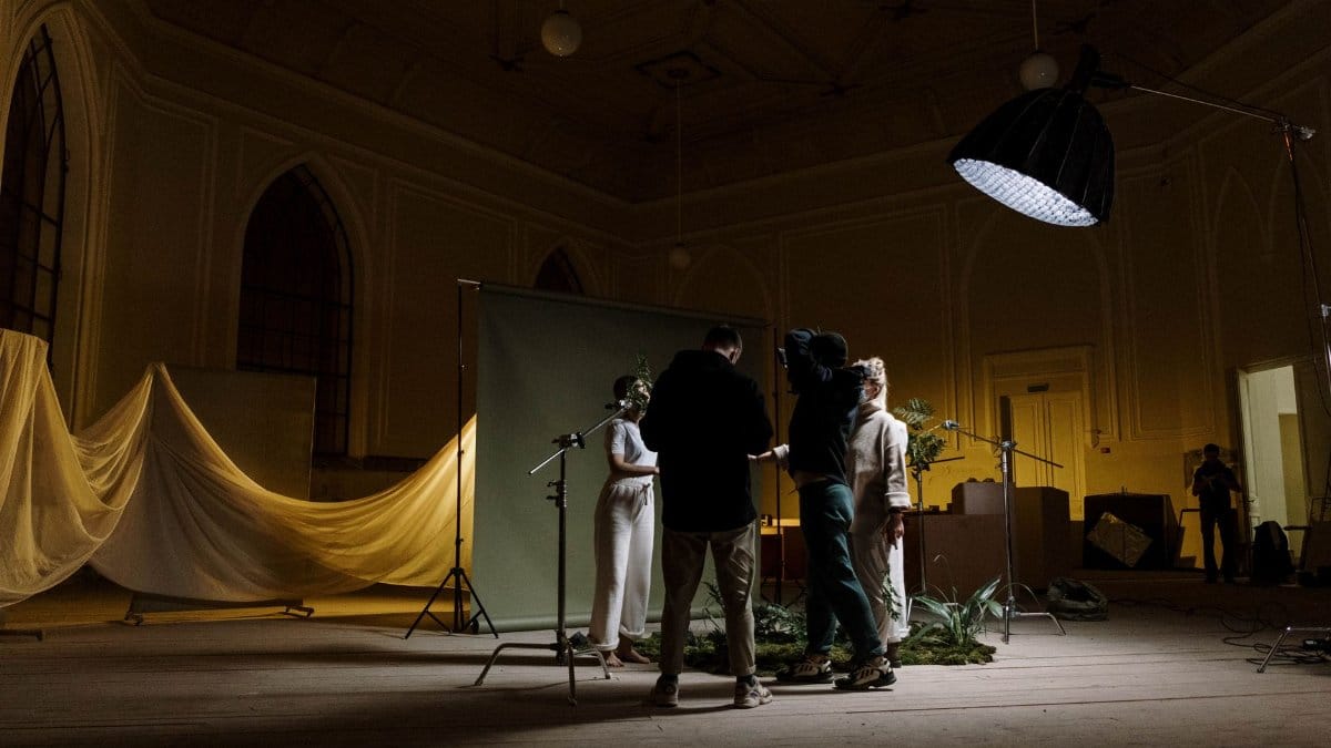 A photography crew setting up lighting and background indoors for a photo shoot.