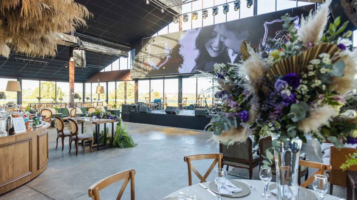 Stylish wedding reception featuring elegant floral decor and stage with seating arrangement.