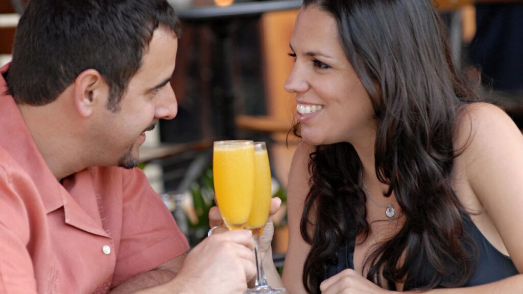 Happy couple toasting with mimosas at a Miami Beach cafe. Perfect for lifestyle and travel themes.