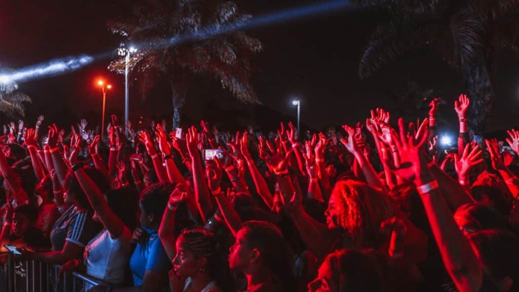 A lively crowd enjoying a night outdoor music festival under bright stage lights.