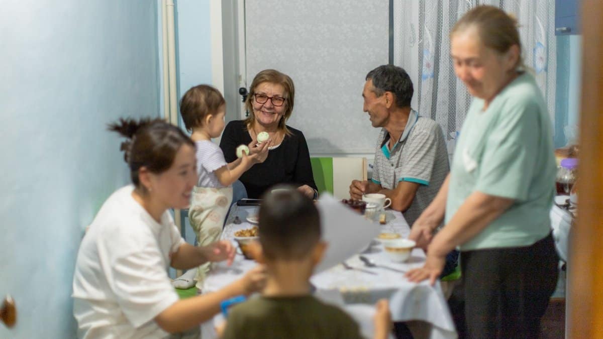 A family enjoying a meal together, sharing conversations and laughter indoors.