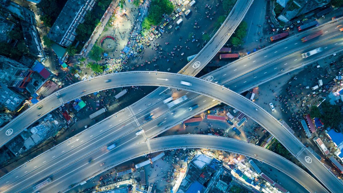 Dynamic aerial shot of a bustling city highway intersection at night.