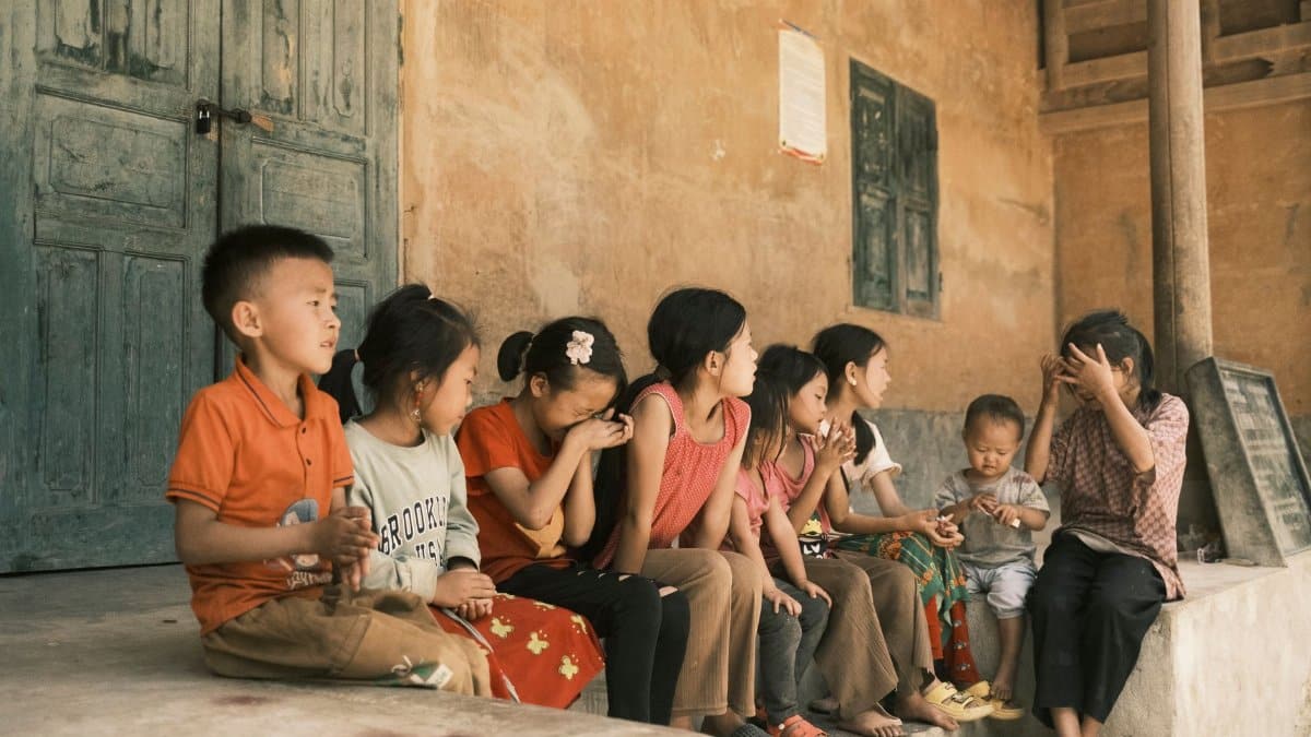 A group of children sitting on a rustic porch sharing a moment outdoors together.