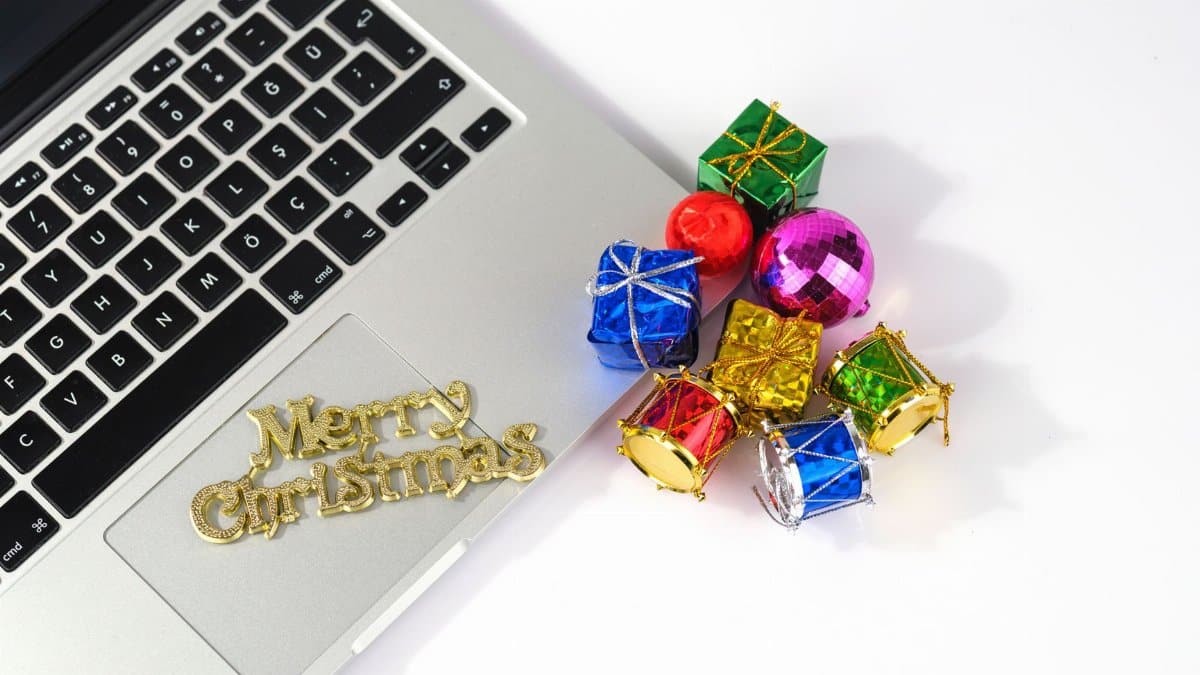 A laptop adorned with Christmas decorations and ornaments adding festive cheer.