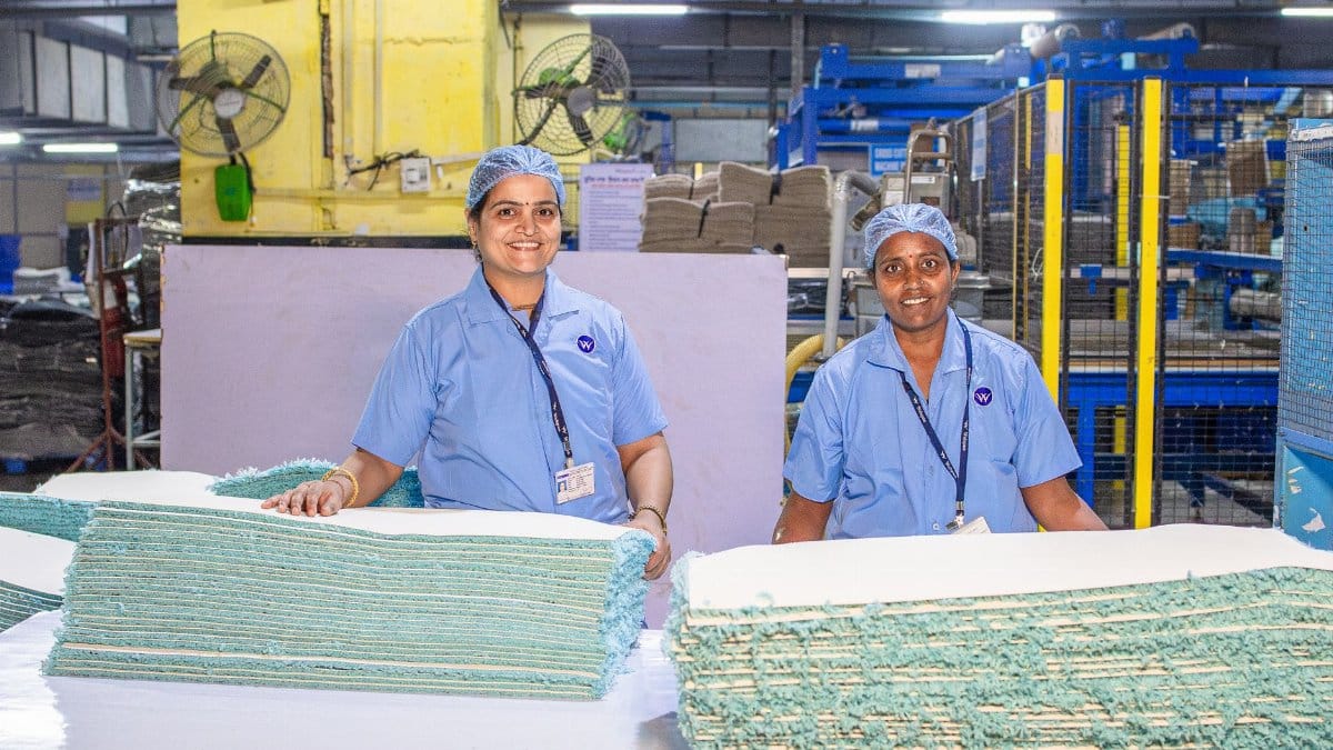 Two Indian female factory workers smiling in textile manufacturing facility.