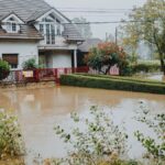A suburban house surrounded by floodwaters after heavy rain, showing impact of natural disaster.