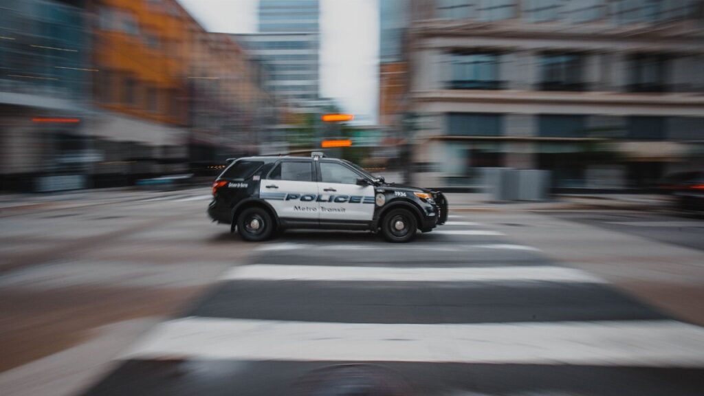 Blurry image of a police car moving quickly in an urban street showcasing motion and speed.