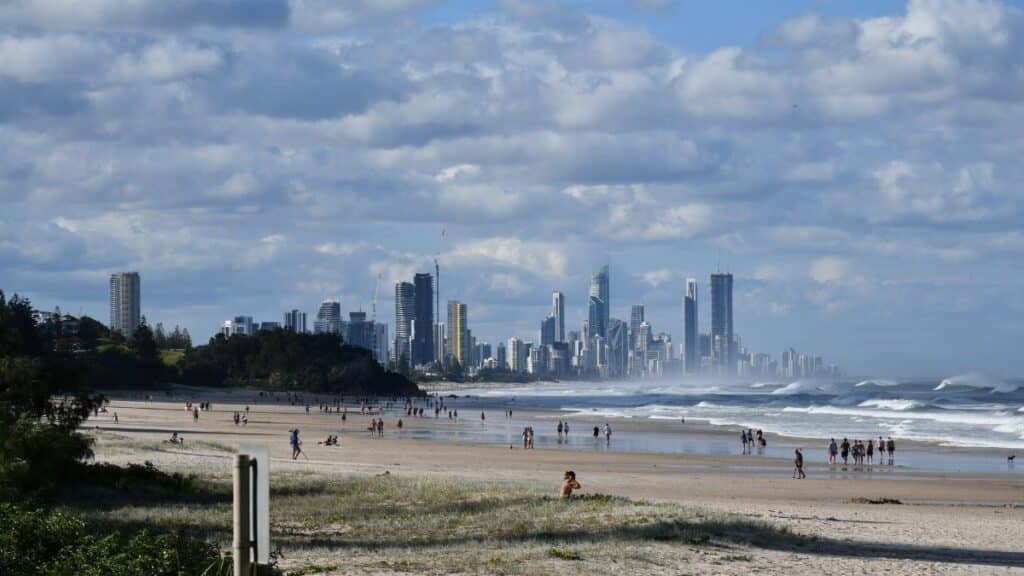 Picturesque view of Gold Coast beach with city skyline under a vibrant sky, capturing surf and sand.