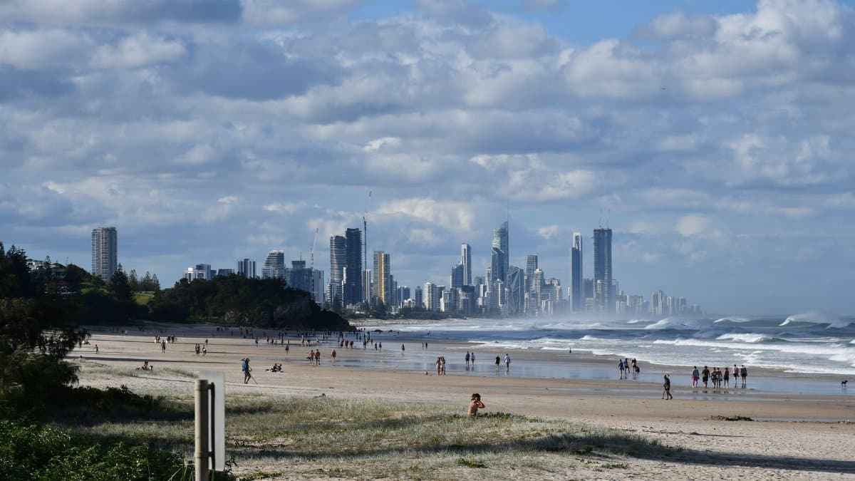 Picturesque view of Gold Coast beach with city skyline under a vibrant sky, capturing surf and sand.