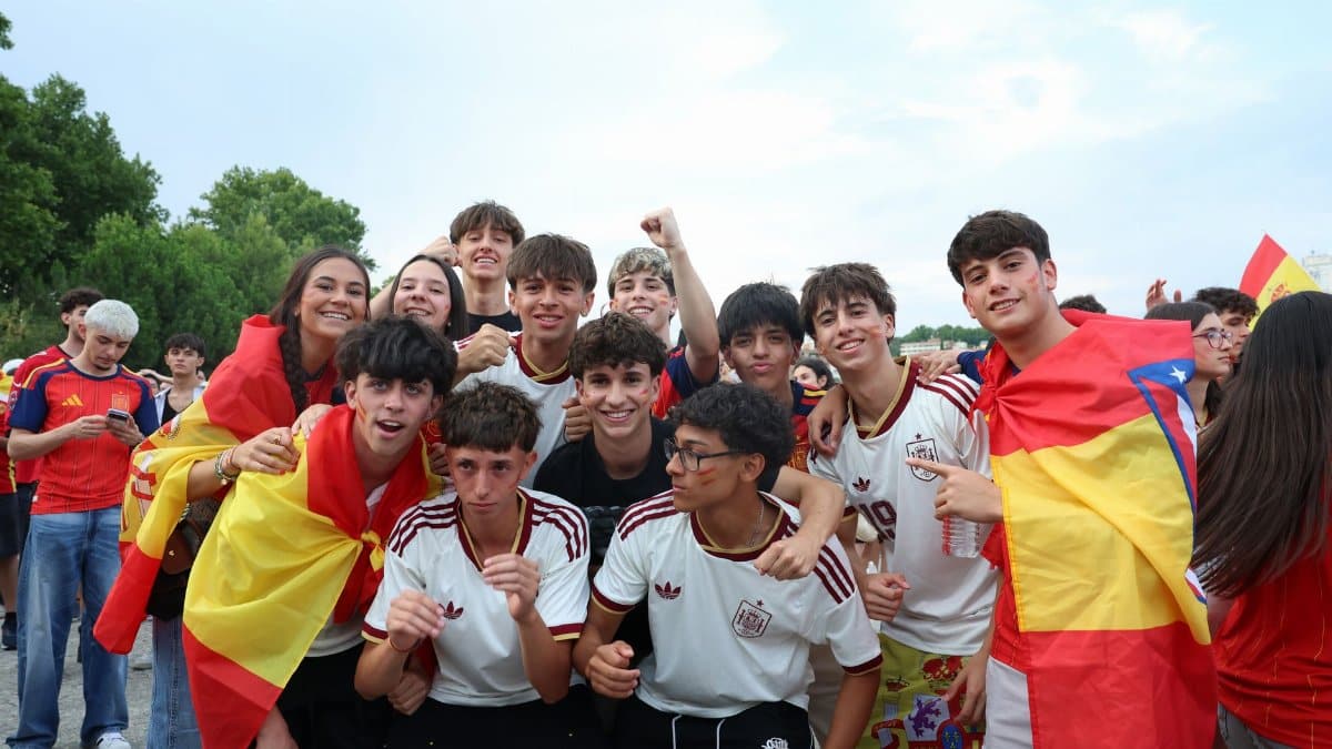 Group of young Spanish fans celebrating their team outdoors with flags and excitement.