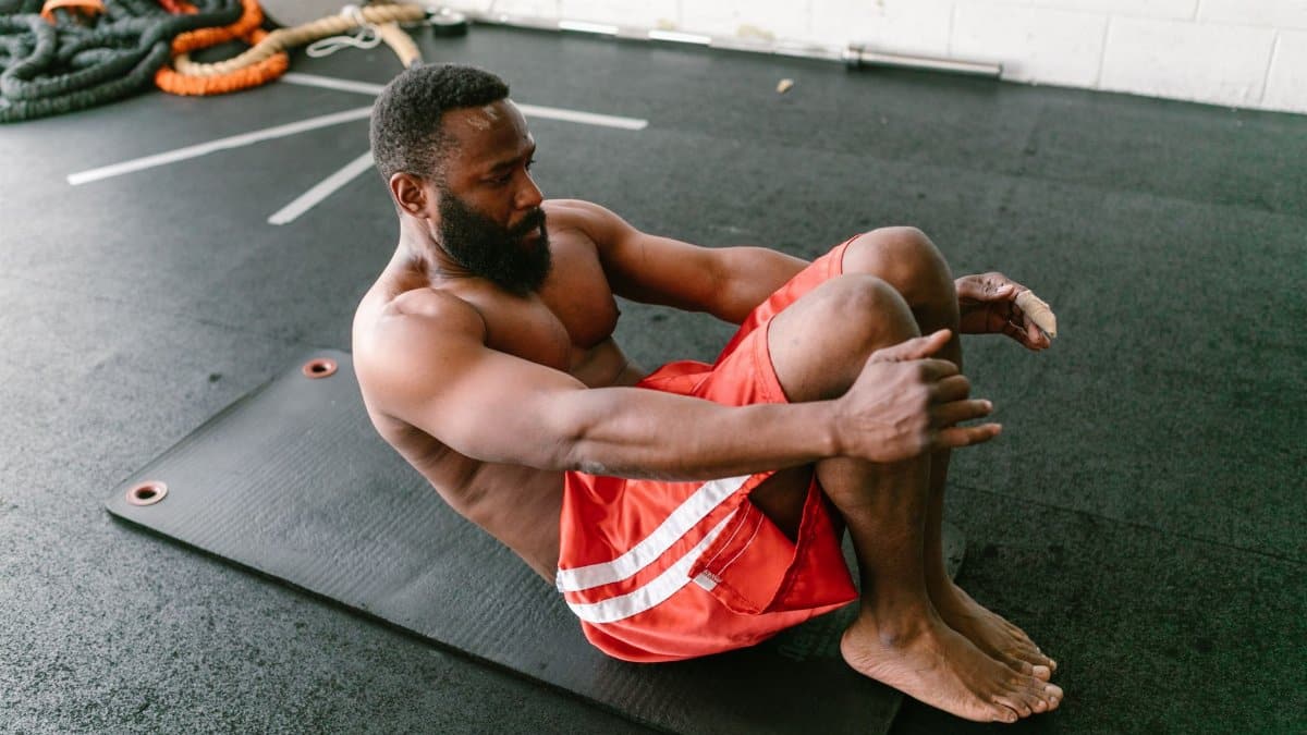 A physically fit man doing sit-ups on a mat indoors, focusing on core strength.