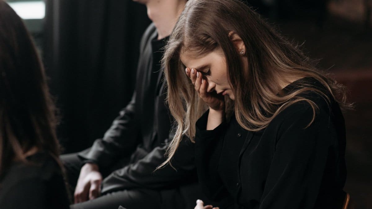 A woman in black clothing expresses sorrow at a funeral, reflecting on loss.