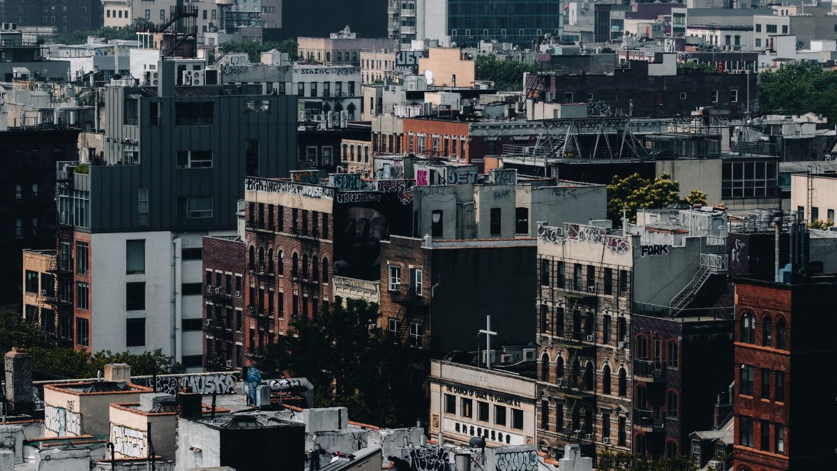 Aerial view of diverse urban rooftops in New York City, showcasing graffiti and architectural variety.