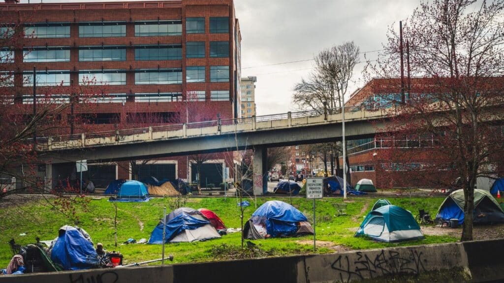 Homeless encampment with tents in downtown Portland under an overpass, capturing social issues.