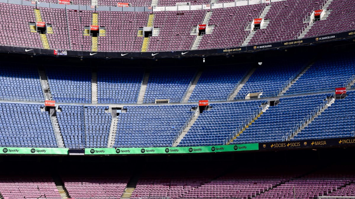 Wide-angle view of the empty stands at Camp Nou Stadium in Barcelona displaying vibrant seat colors.