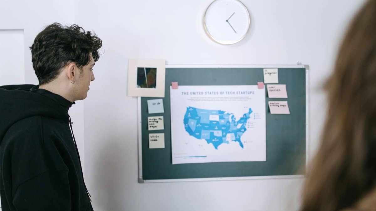 Young professionals discussing a map of US tech startups in a modern office setting.