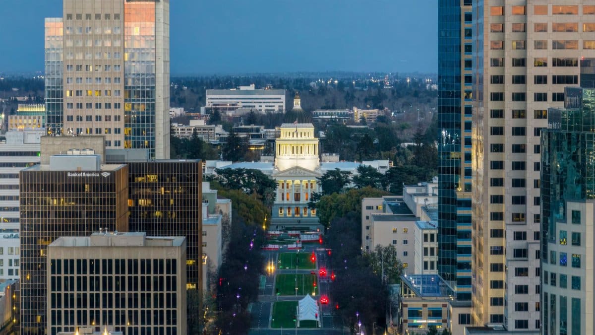 Aerial view of the Sacramento skyline featuring the California State Capitol illuminated at dusk.
