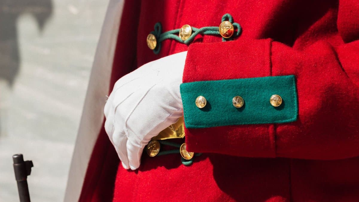 Detailed shot of a guard's vibrant red and green ceremonial uniform with gold buttons.