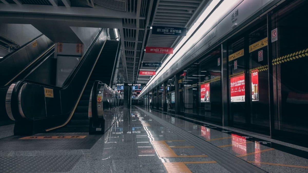 Empty modern subway station featuring escalators and reflective floors, showcasing urban transportation design.