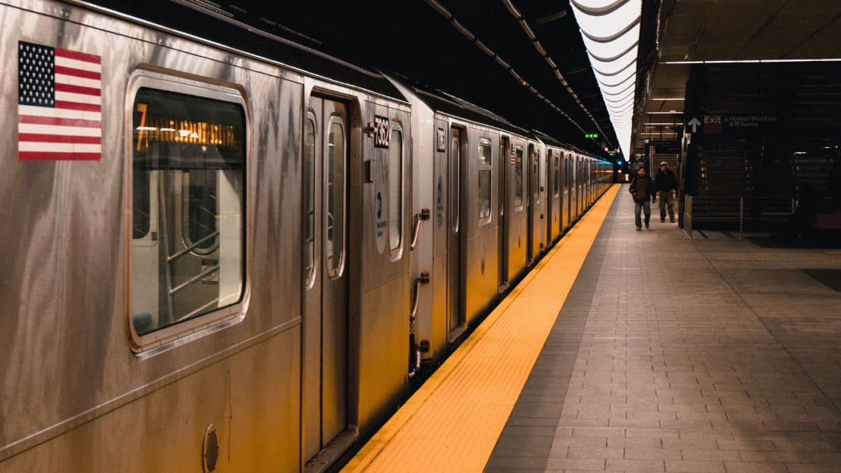 Image of a New York subway train at an underground station platform with an American flag.