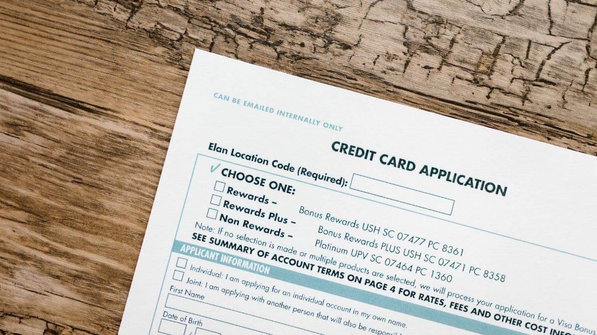 Top view of a credit card application form on rustic wooden background.