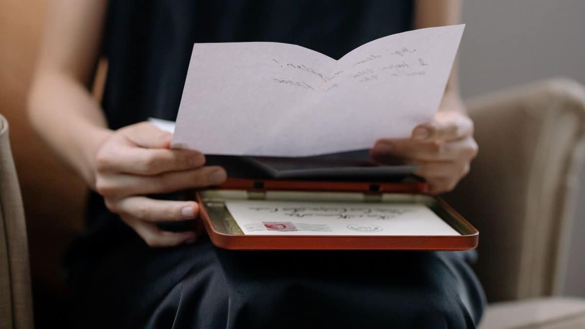 An adult woman holding and reading a handwritten letter in an intimate home setting.