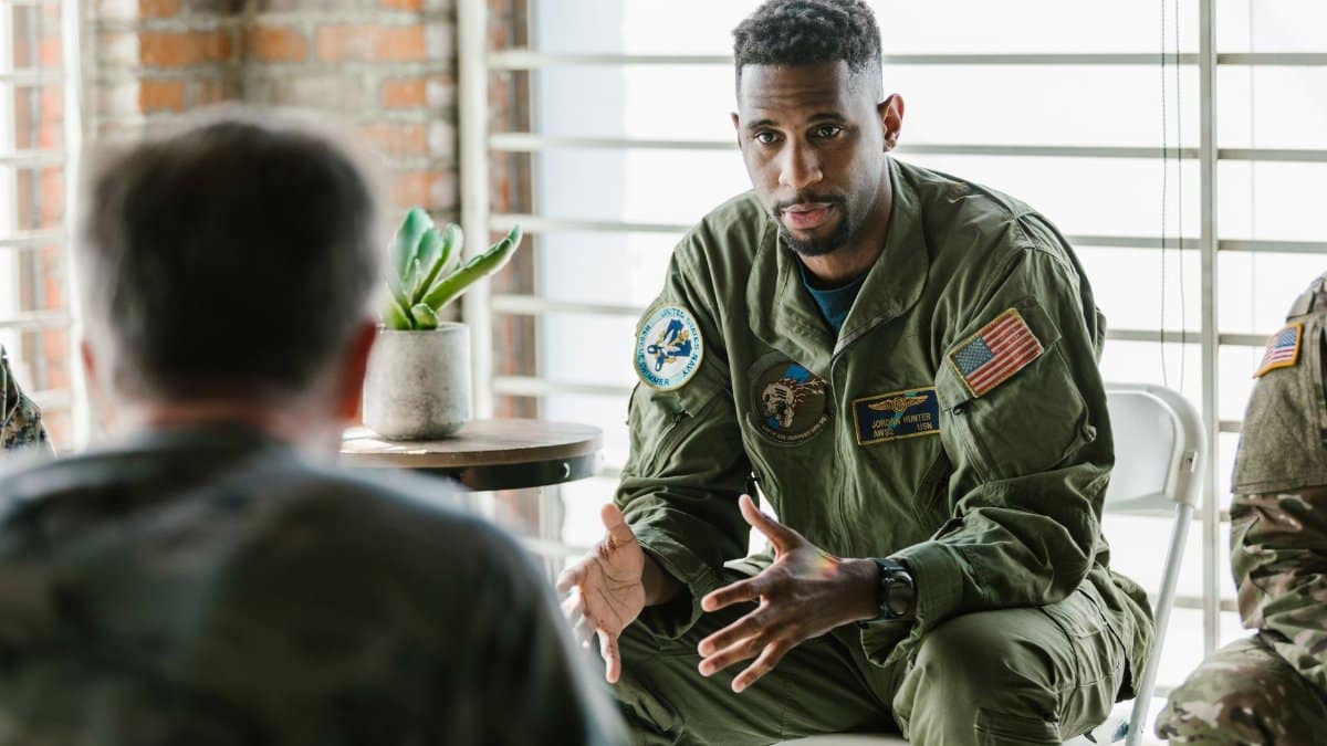 A group of military veterans participate in a supportive therapy session indoors.