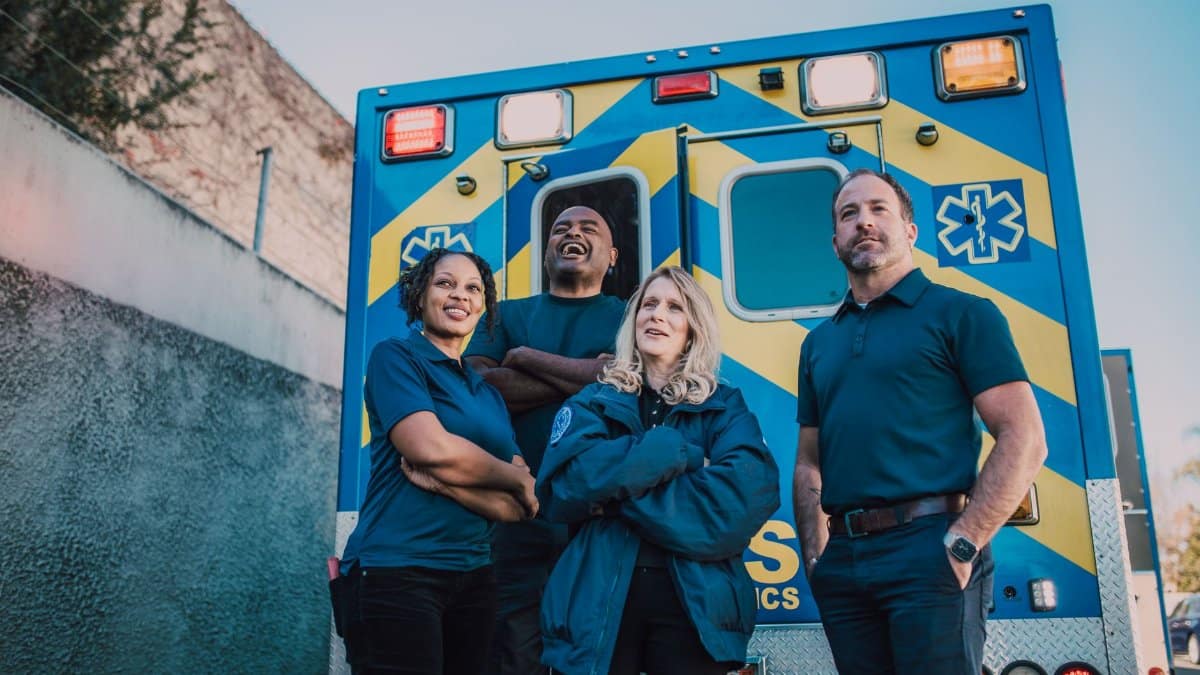Diverse paramedic team confident in front of ambulance vehicle outdoors.