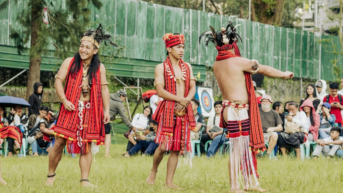 Men performing a traditional dance in vibrant attire during a cultural festival outdoors.
