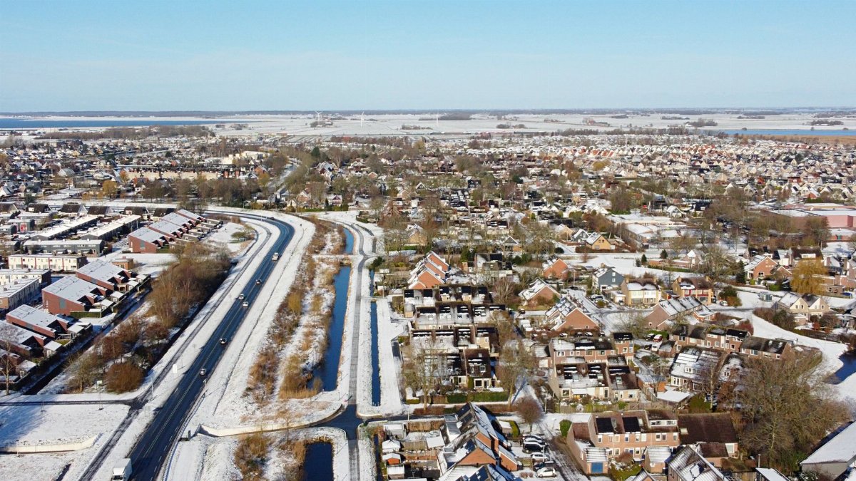 Aerial view of a suburban residential district covered in snow, showing roads, houses, and urban planning.