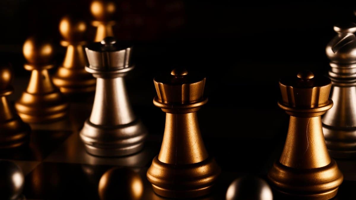 Close-up still life of golden and silver chess pieces on a board, creating a dramatic and strategic atmosphere.