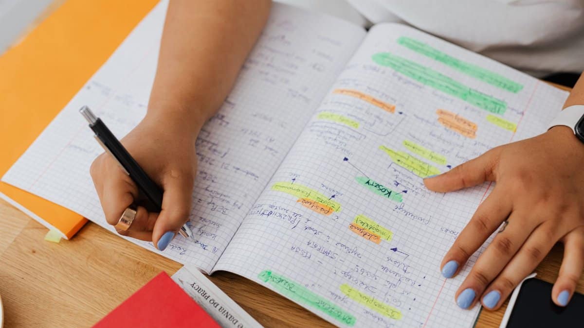A person writing and highlighting notes in a graph notebook. Ideal for education and productivity themes.