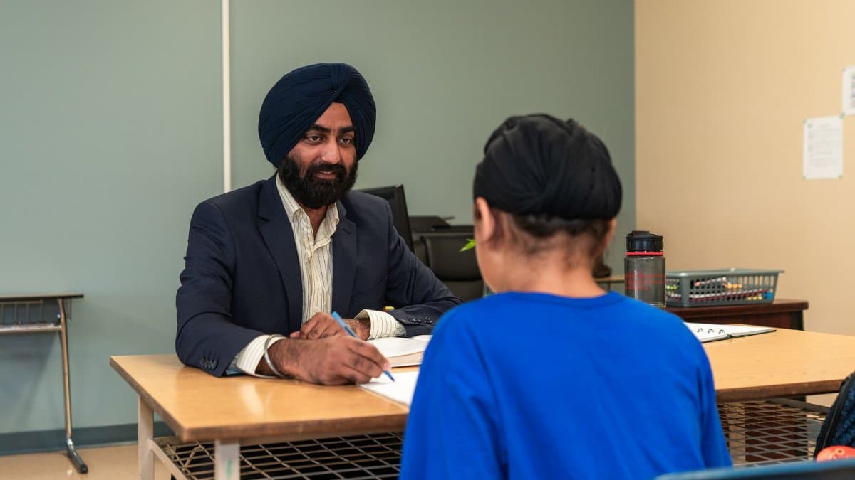A teacher and student engaging in a one-on-one discussion in a classroom setting.