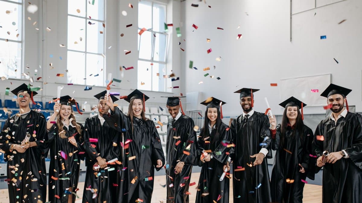 Joyful graduates celebrate commencement with confetti indoors, symbolizing achievement and diversity.