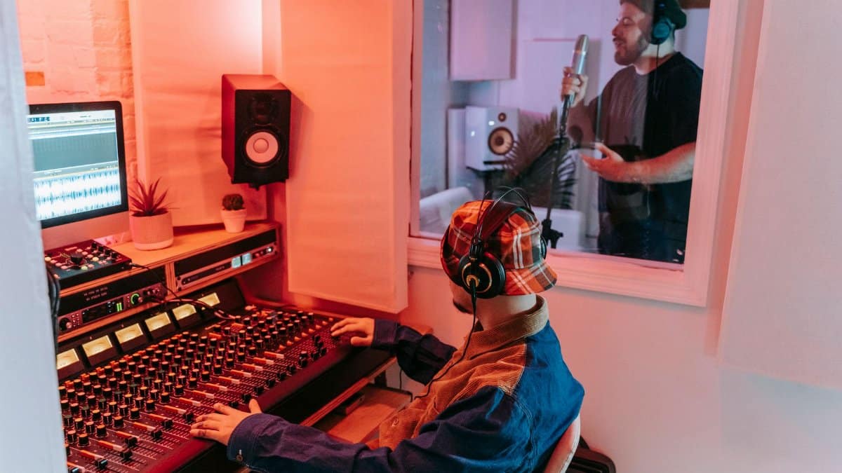 Two men engaged in a vocal recording session in a modern music studio, highlighting sound equipment.