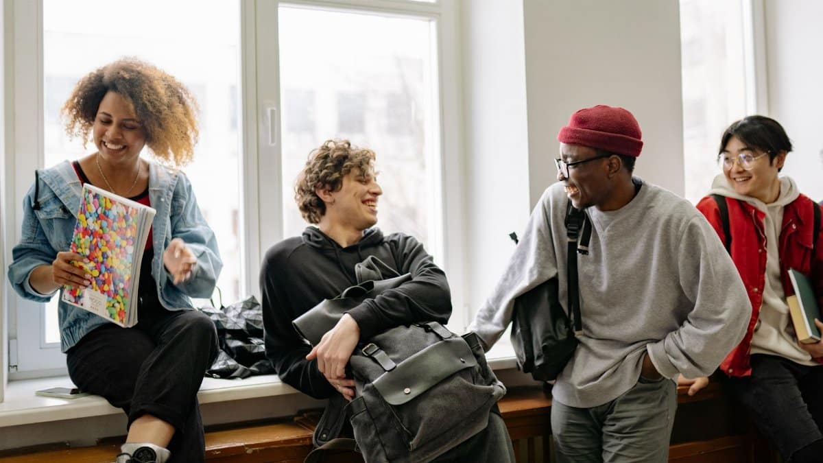 A cheerful and diverse group of students socializing in a well-lit indoor setting, embracing togetherness.