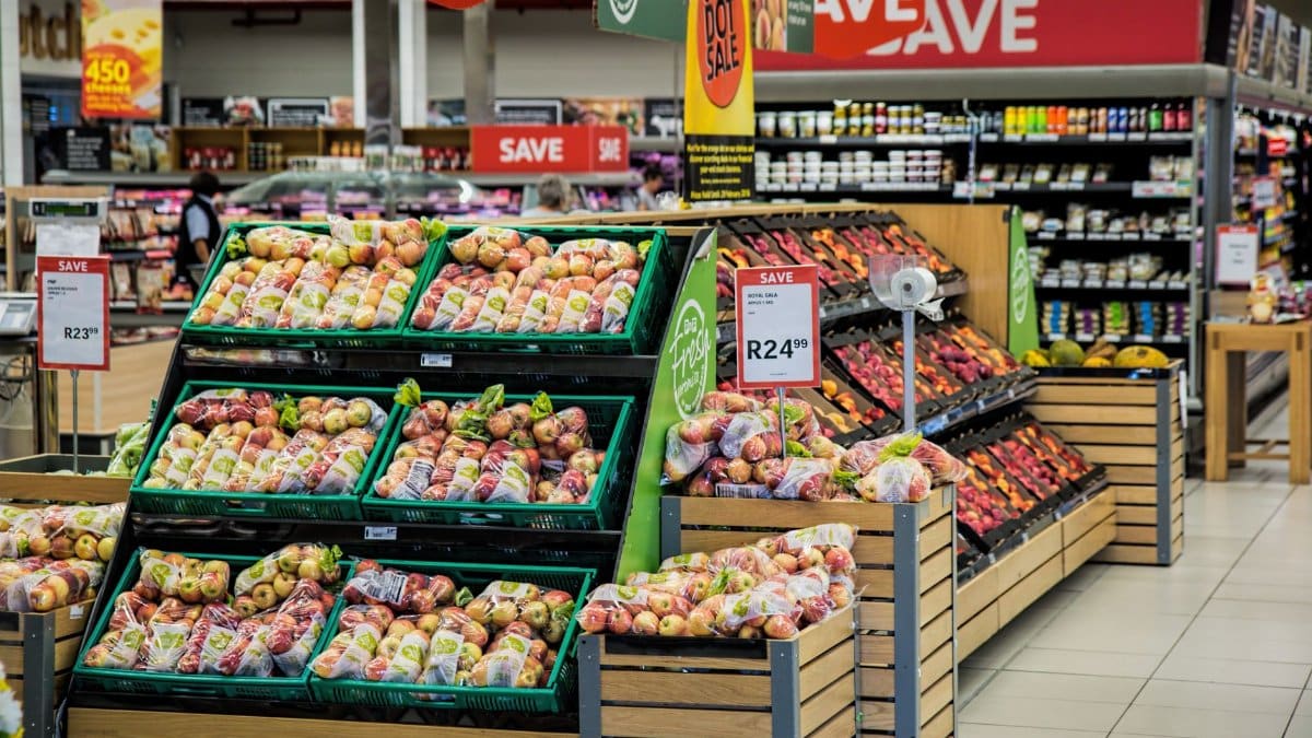 Colorful produce aisle in a supermarket showcasing fresh apples with discount signage.