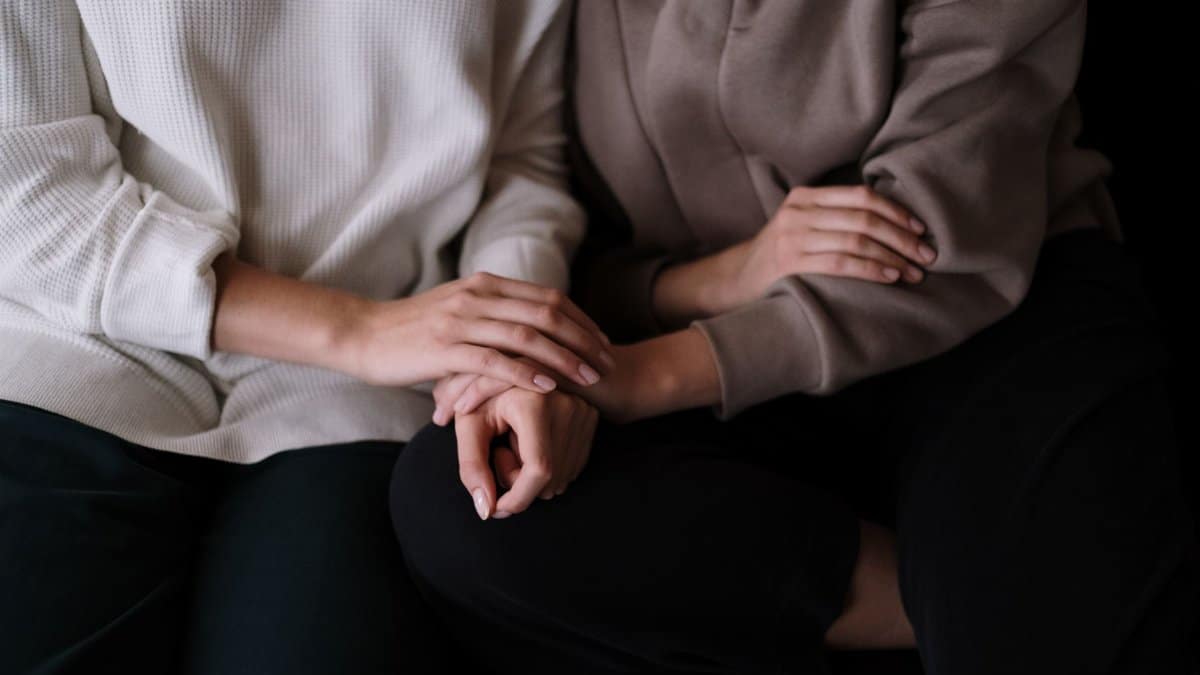 Two individuals sitting together, providing comfort and support with gentle touch.
