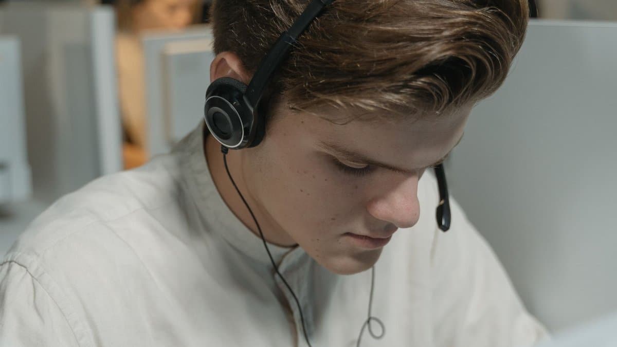 A call center agent wearing headphones focuses on providing customer support in an office setting.