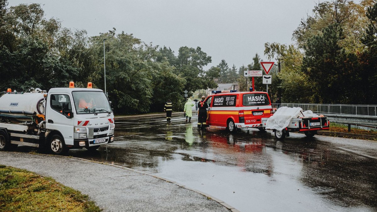 Emergency services attending a scene on a rainy road with rescue vehicles and personnel.