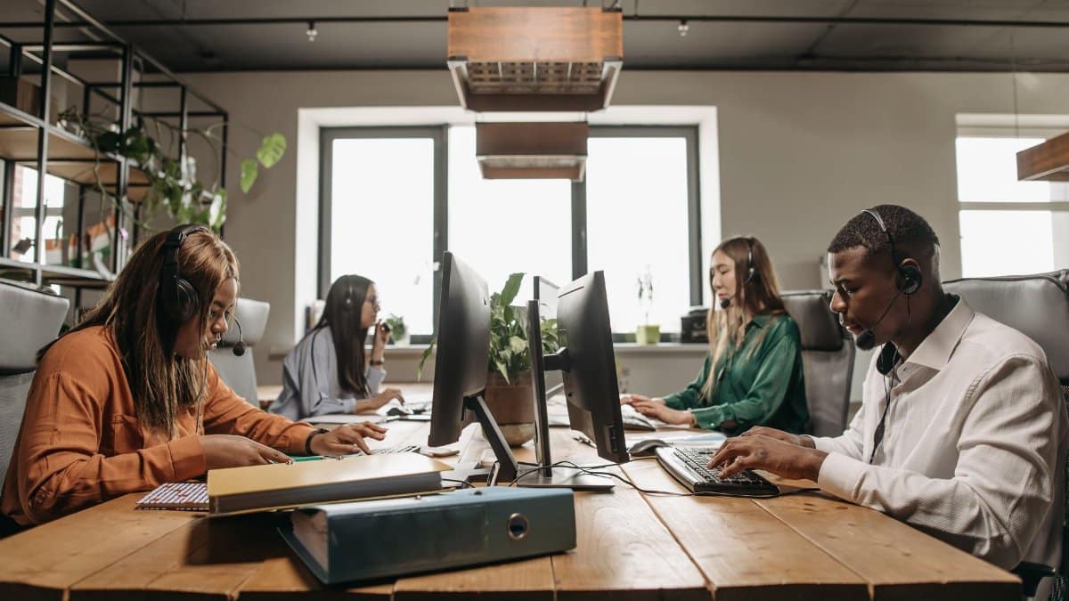 A diverse group of employees collaborating with headsets in a modern office setting.