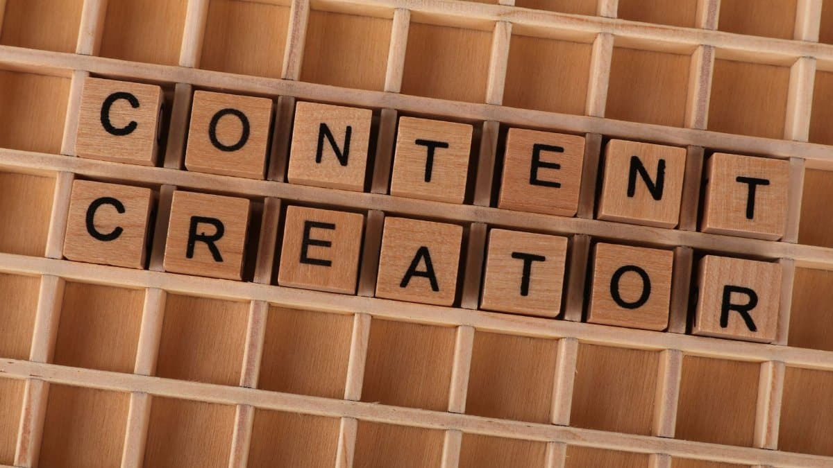 Wooden block letters spelling 'Content Creator' on a grid background. Ideal for digital marketing themes.