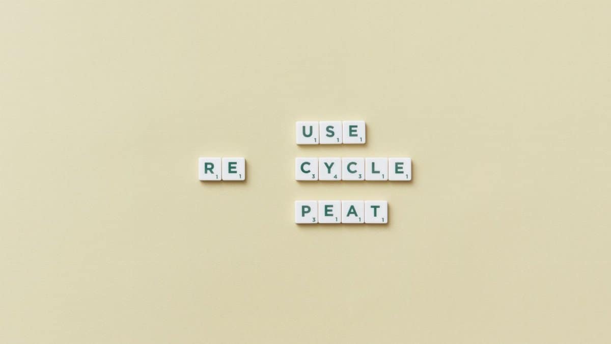 Letter tiles spelling 'reuse recycle repeat' on a simple background, promoting sustainability.